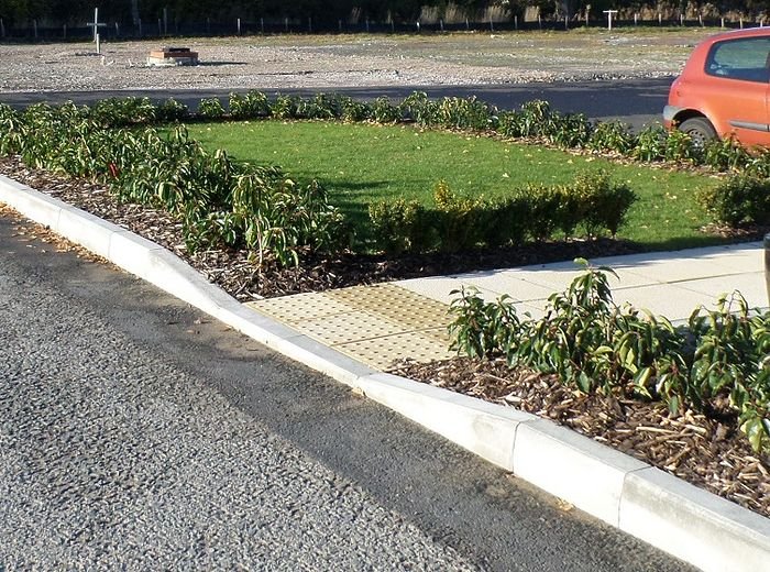 A commercial frontage with a new shrub bed, kerbing and gravel mulch beside the road