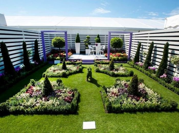 Formal beds with dark topiary obelisks, clipped edging and dense flower planting