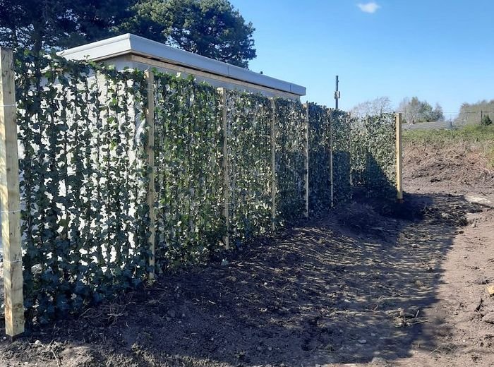 Instant screening panels installed along a boundary, with the ground freshly turned
