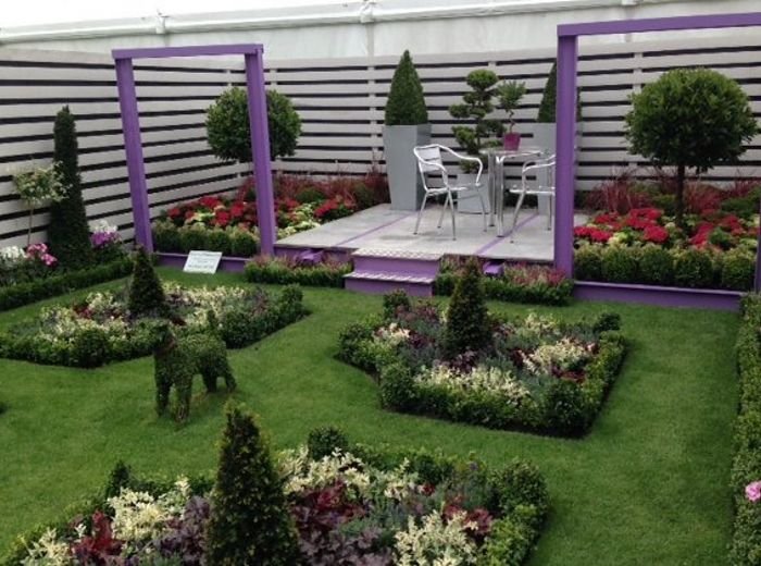 A display garden with painted timber frames, clipped topiary and a raised seating deck