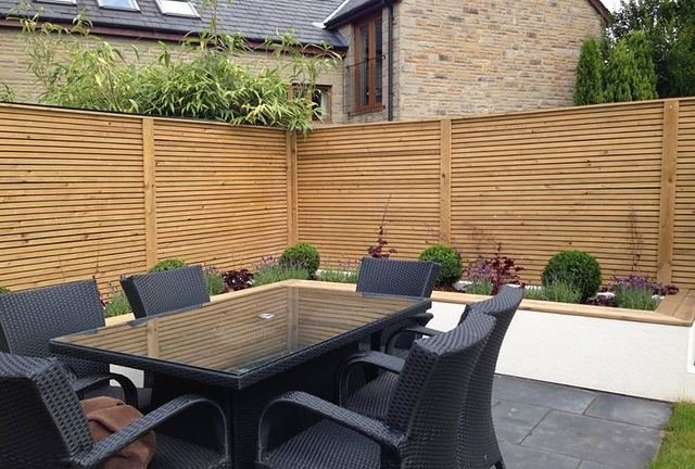 A finished patio with an outdoor dining set, new fencing and planted beds